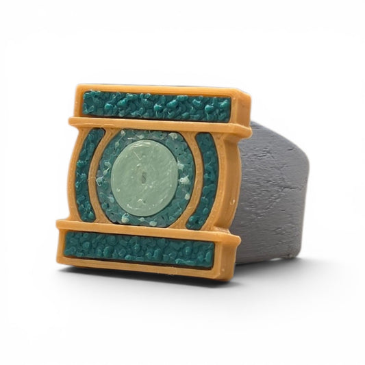 3D printed gold and teal power ring with glow in the dark center stone side profile view